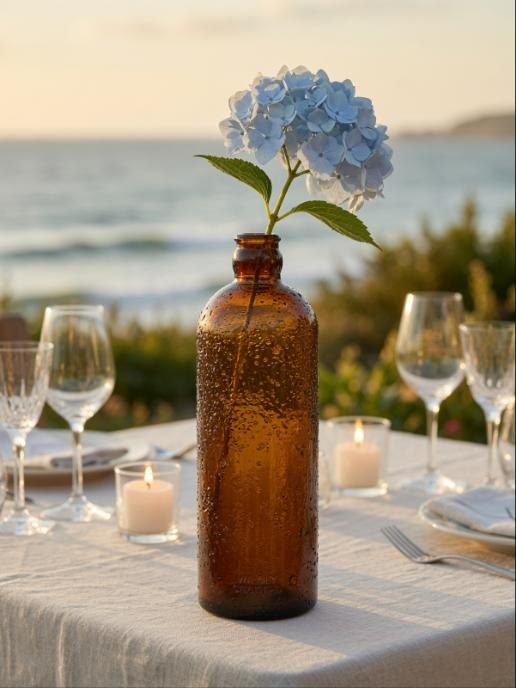 Grand soliflore Compoz en verre ambré avec hortensia bleu, table de mariage face à la mer au coucher du soleil