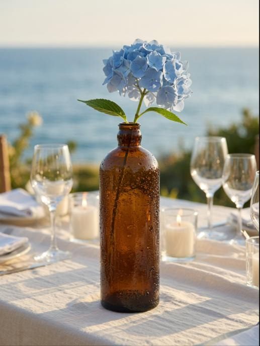Grand soliflore Compoz en verre ambré avec hortensia bleu, table de mariage face à la mer, chandelles